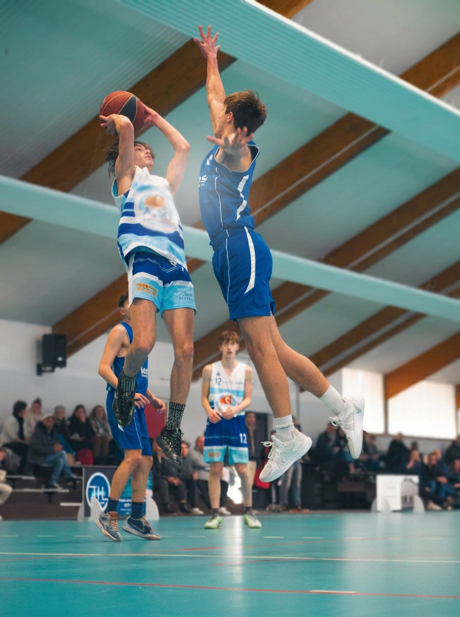 Jeunes basketteurs en plein saut pendant un match, public flouté en arrière-plan