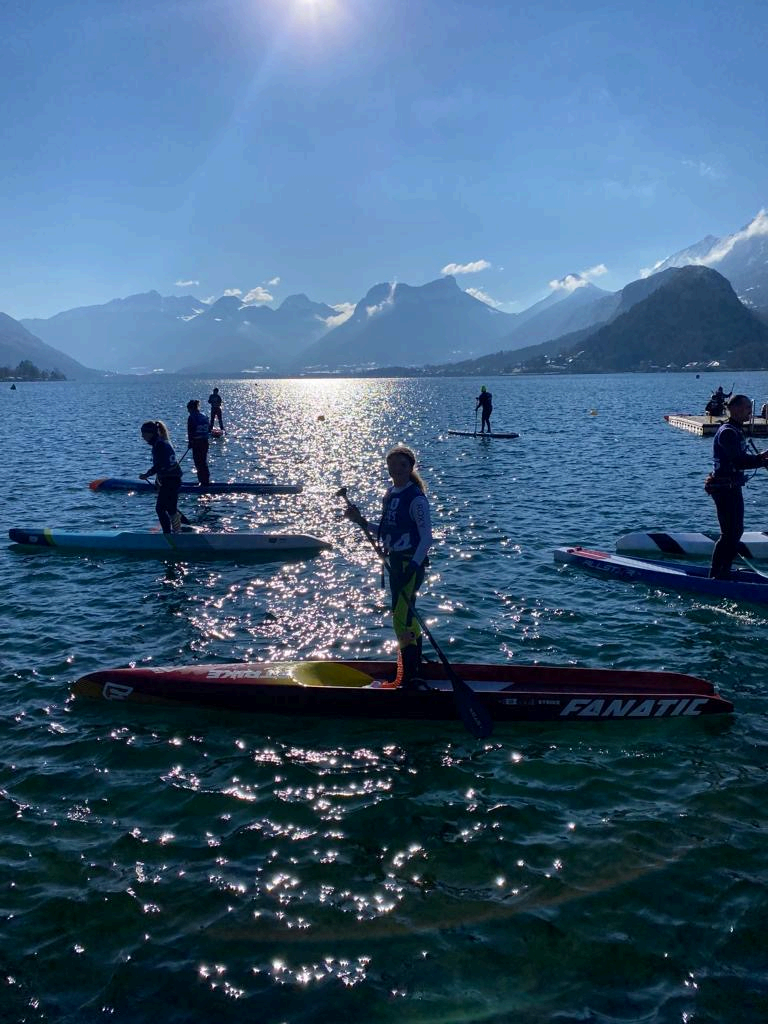 Groupe de pratiquants de stand up paddle sur un lac entouré de montagnes